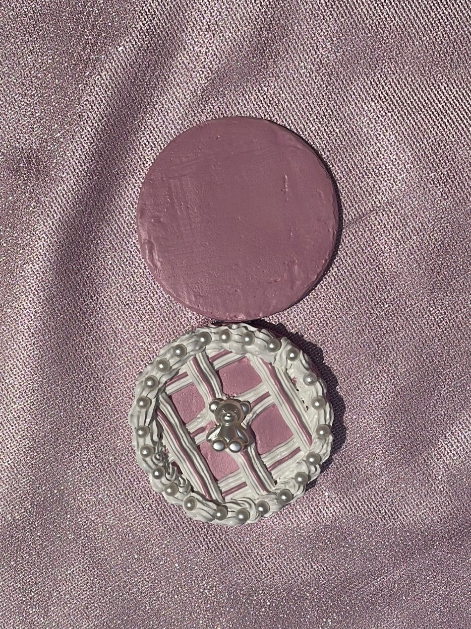 a compact mirror decorated to look like a pink cake with pearl details