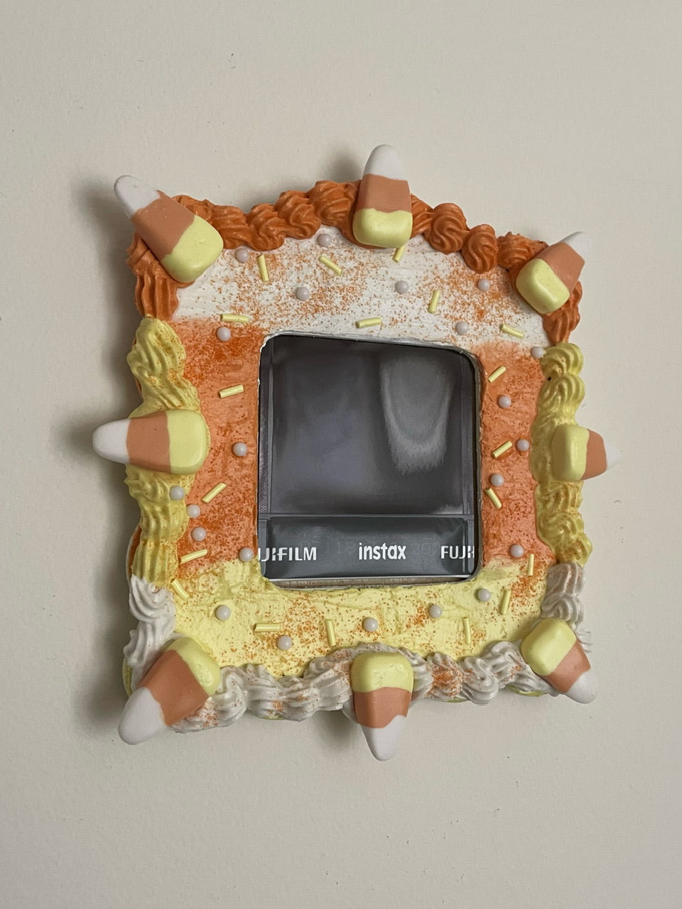 a mini picture frame decorated like a candy corn coloured cake hanging on a white wall