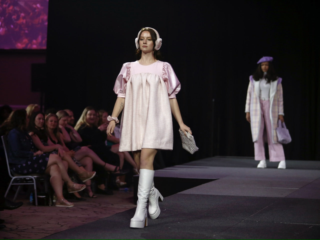 a model wearing a pink puffy mini dress walking down a runway