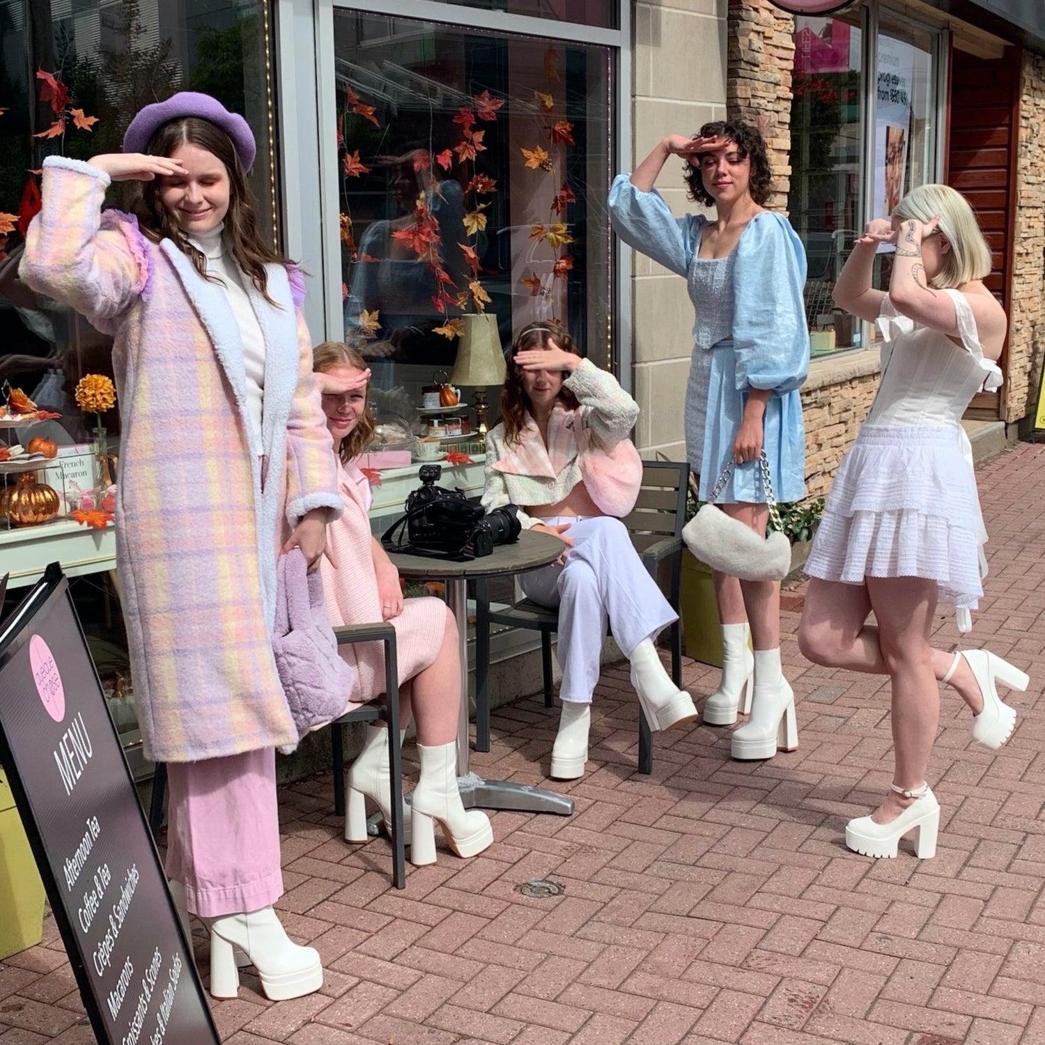 5 women standing outside of a cafe wearing pastel wintery outfits