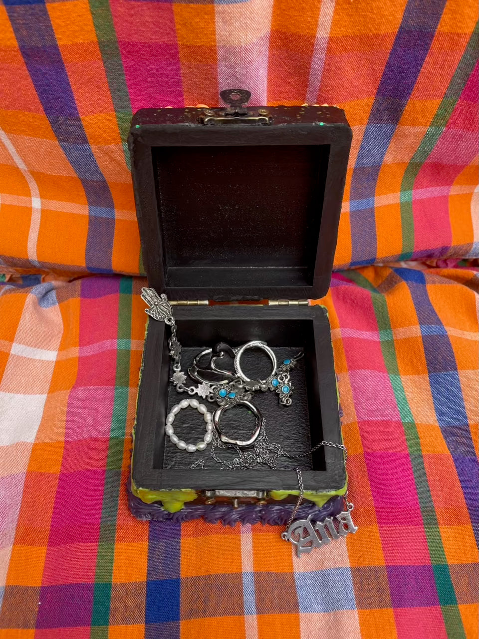 a small, open hinged box with jewelry inside of it