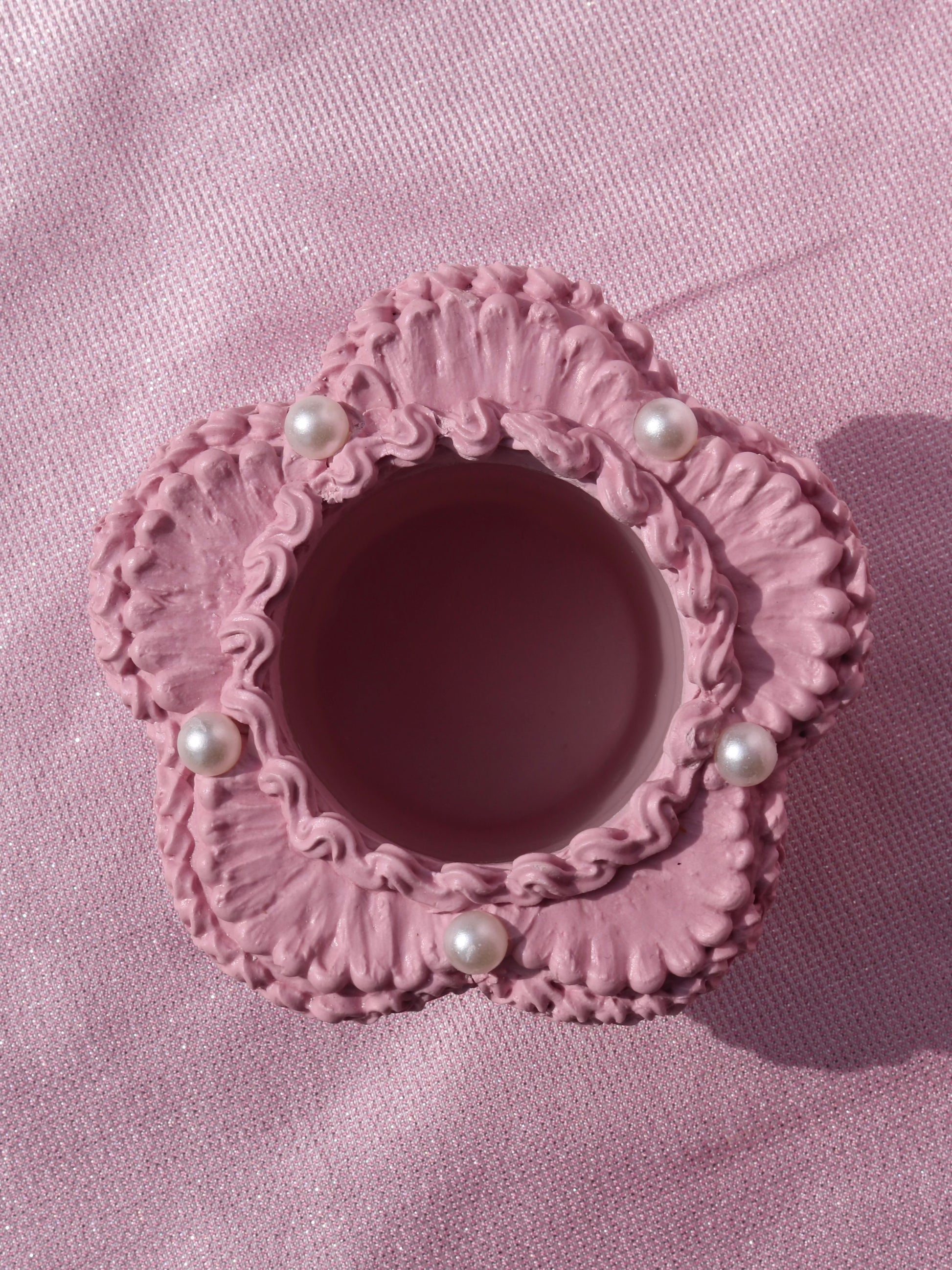 a flower shaped candle holder decorated to look like a pink cake with pearl details