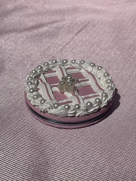 a closed compact mirror decorated to look like a pink cake with pearl details